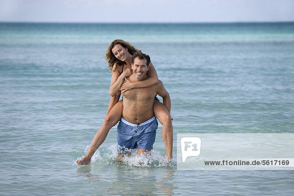 Man giving woman piggyback at beach  portrait