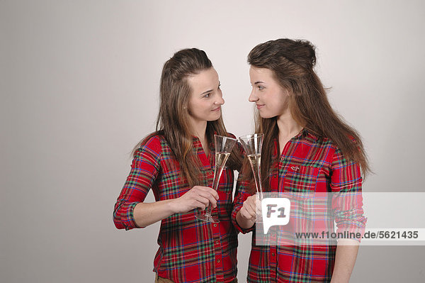 Twin sisters toasting each other with champagne glasses