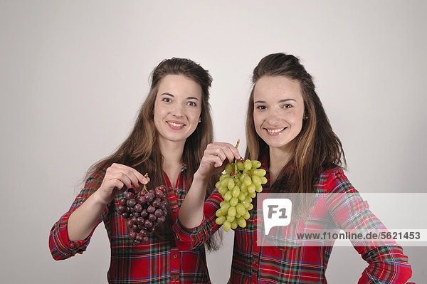 Zwillingsschwestern mit Weintrauben
