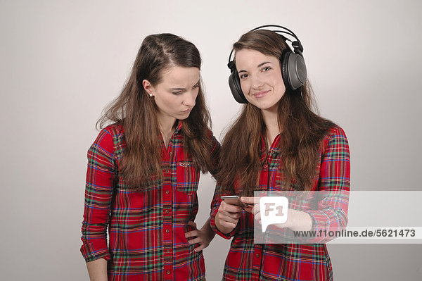 Zwillingsschwestern  die eine hält einen iPod  die andere mit Kopfhörern