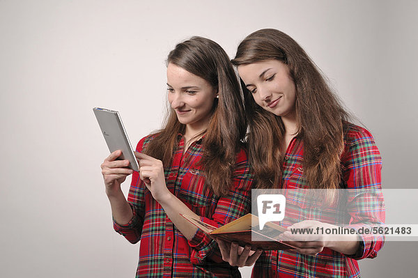 Zwillingsschwestern lesen  die eine in einem modernen E-Book-Reader  die andere in einem Buch