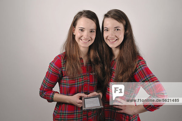 Twin sisters looking at an e-book reader