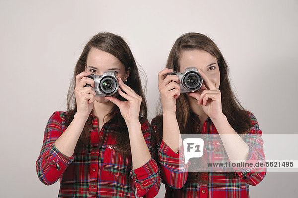 Zwillingsschwestern mit Digitalkameras