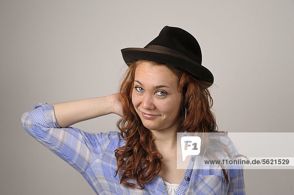 Junge Frau mit roten Haaren und braunem Filzhut