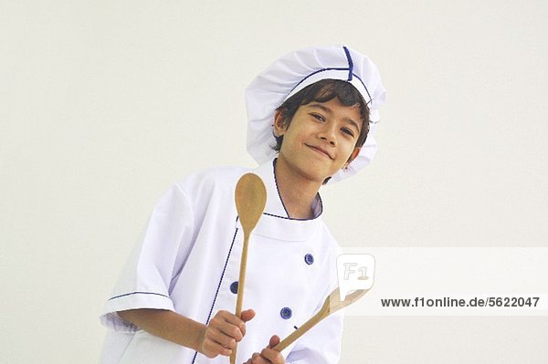 Junge als Koch mit Holzlöffeln