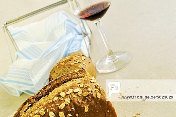 Angeschnittene Brote  dahinter Glas Rotwein & Servietten