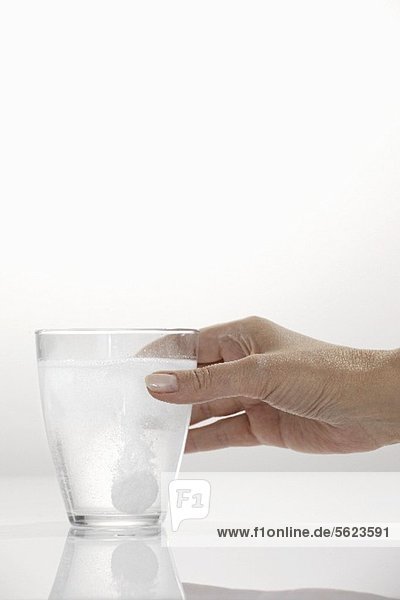 Hand hält Glas mit Brausetablette