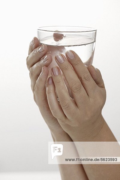 Hände halten Wasserglas