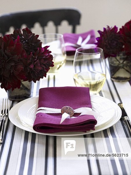 A place setting with a white plate and a pink napkin