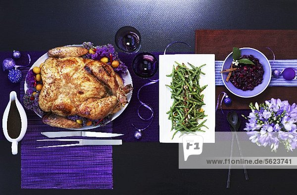 Chinese roasted turkey with green beans on a table with purple decorations