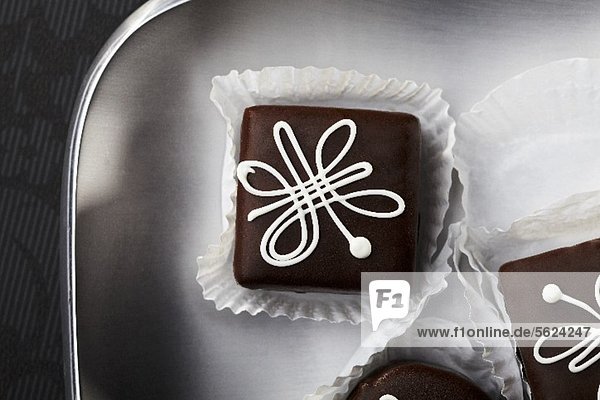 Chocolate petit fours with white icing (seen from above)