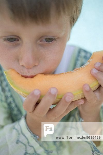 Kleiner Junge isst Melonenspalte