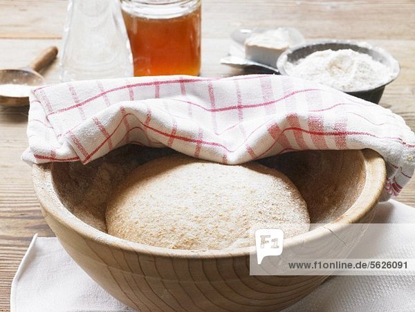 Khorasan wheat dough in a wooden bowl covered with a tea towel