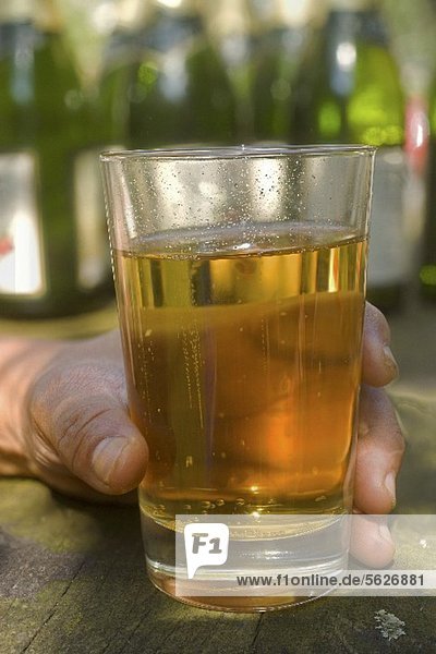 A hand holding a glass of apple wine