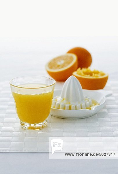Ein Glas Orangensaft  Zitruspresse und Orangen