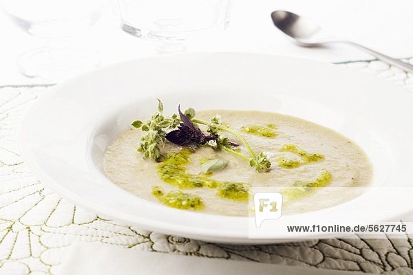 Bowl of Creamy Artichoke Soup with Pesto and Fresh Purple Basil and Lemon Basil