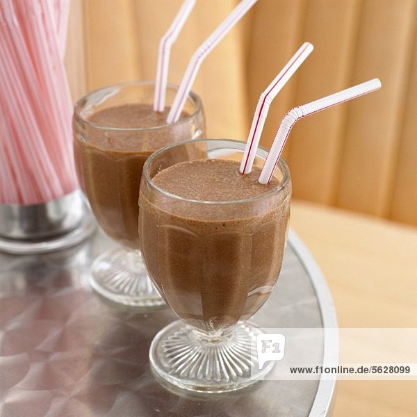 Two chocolate milkshakes with straws