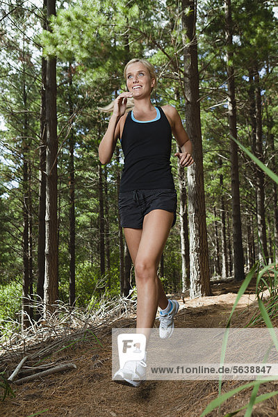 Woman running on dirt path in forest