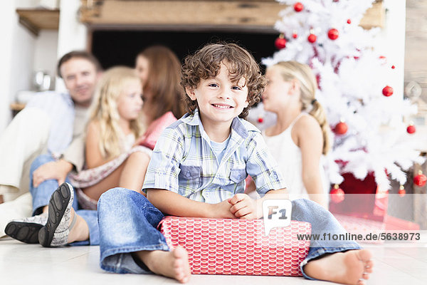 Junge sitzend mit verpacktem Weihnachtsgeschenk