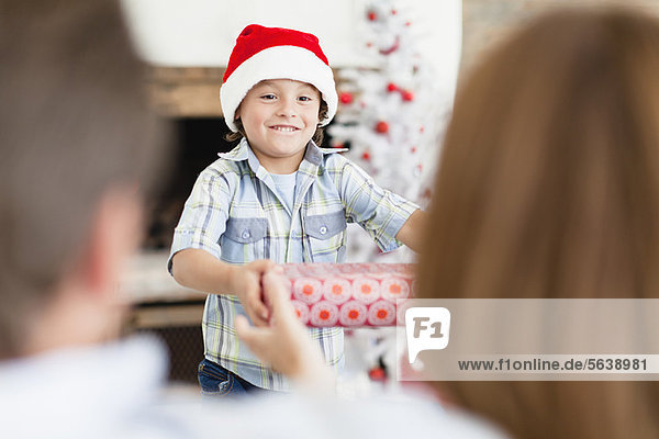 Junge in Weihnachtsmütze mit Weihnachtsgeschenken
