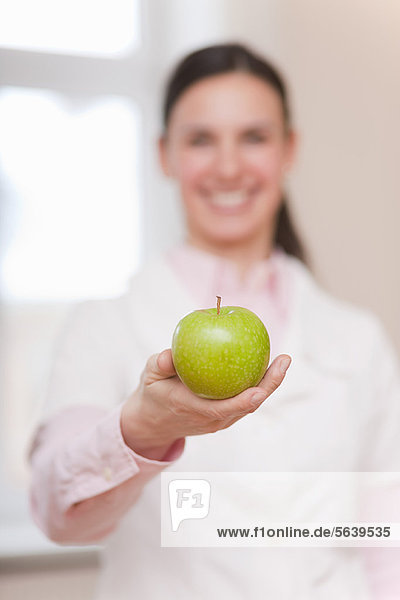 Smiling doctor offering green apple