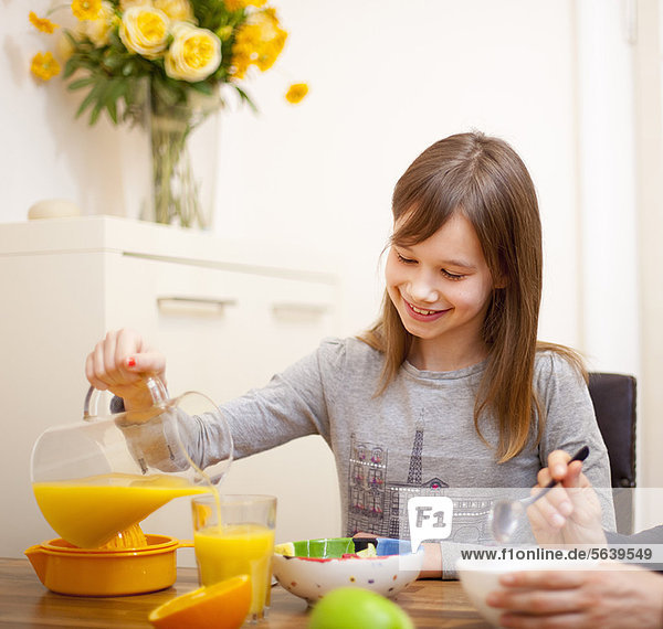 Girl pouring orange juice at table