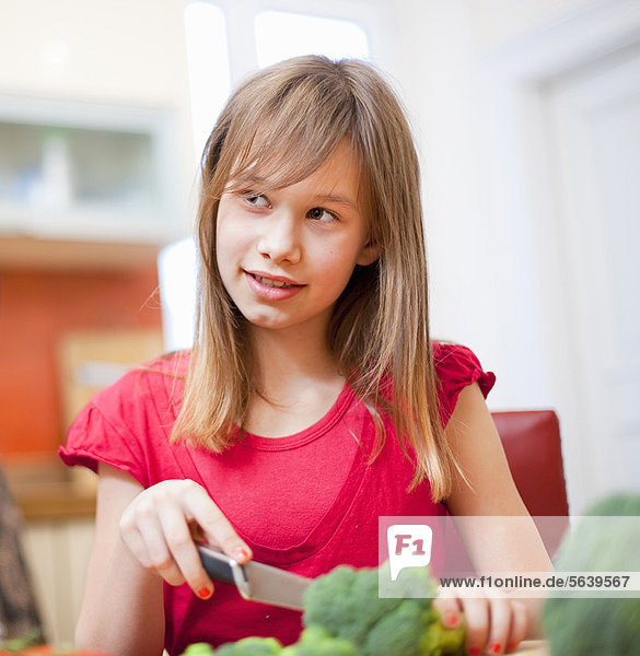 Girl slicing vegetables in kitchen