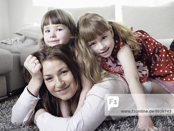 Mother and daughters laying on rug