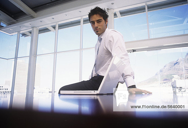 Businessman sitting on desk in office