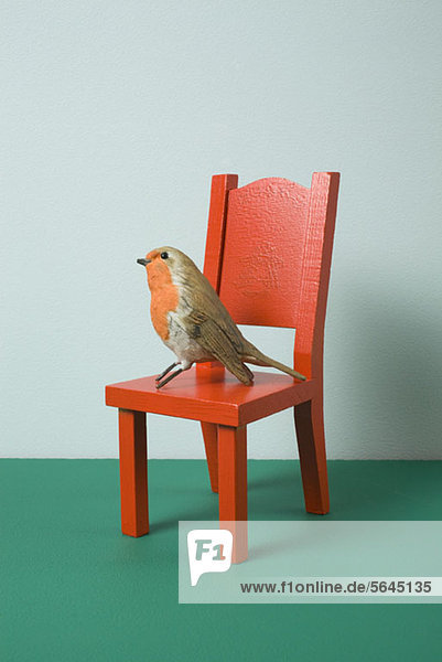 Ein imitierter Vogel sitzt auf einem Miniaturstuhl