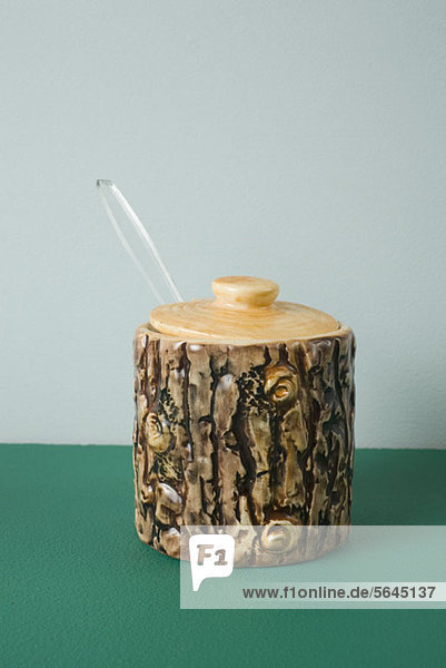 Ein Keramik-Honigglas  das wie Baumrinde aussieht.