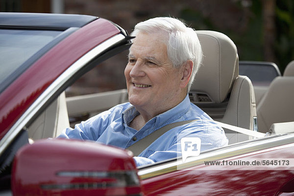A senior man driving a convertible sports car
