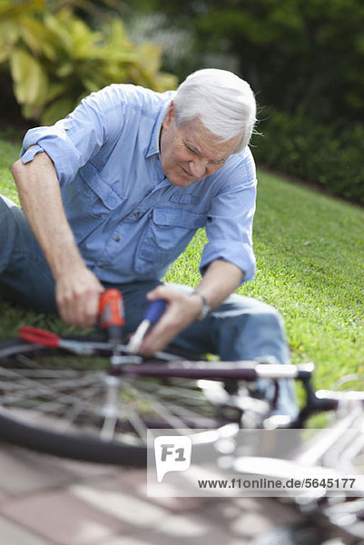Ein älterer Mann  der ein Fahrrad repariert.