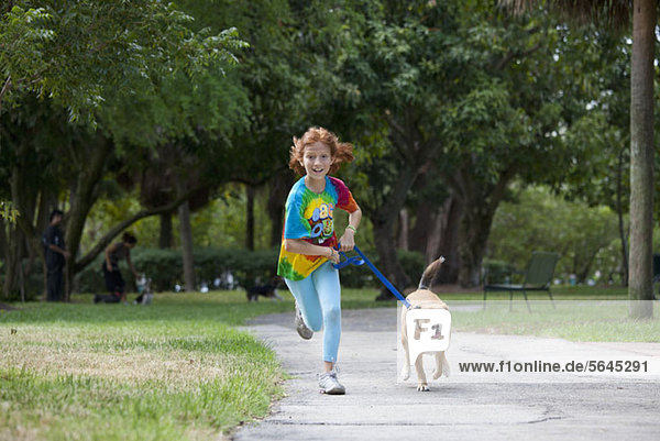Girl running with dog through park