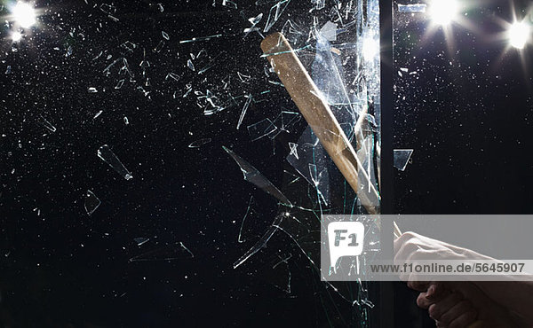 Detail eines Mannes  der mit einem Baseballschläger Glas zerschmettert.