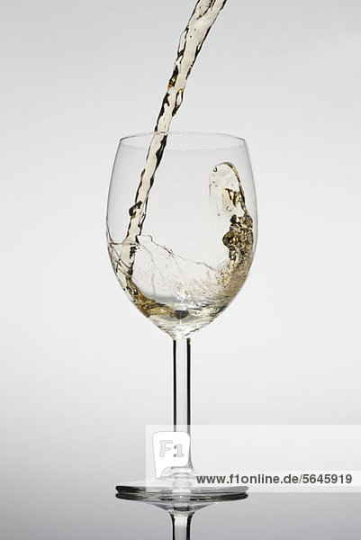 Weißwein wird in ein Glas gegossen