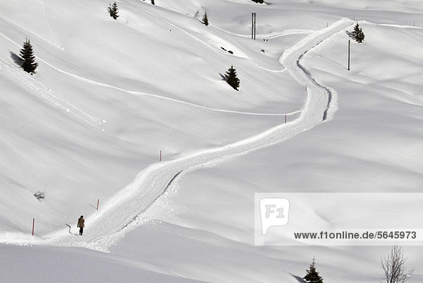 Person  die über einen schneebedeckten Fußweg bergauf geht