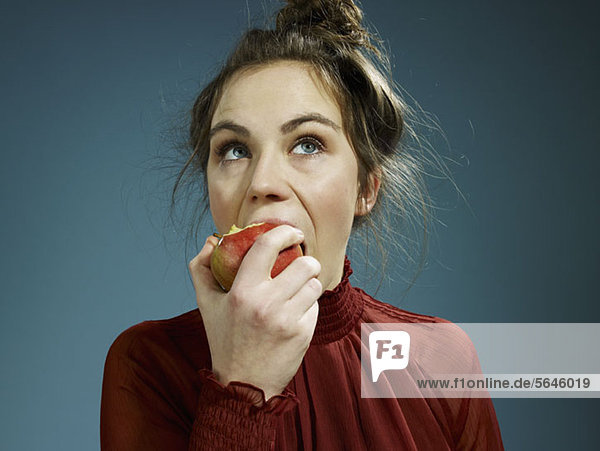 Eine junge Frau,  die einen Apfel isst.