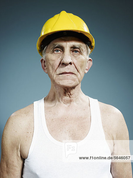 Ein ernster älterer Mann  der einen Schutzhelm und ein Tank-Top trägt.