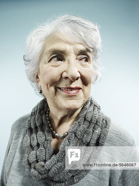 Eine elegante Seniorenfrau lächelt und schaut weg