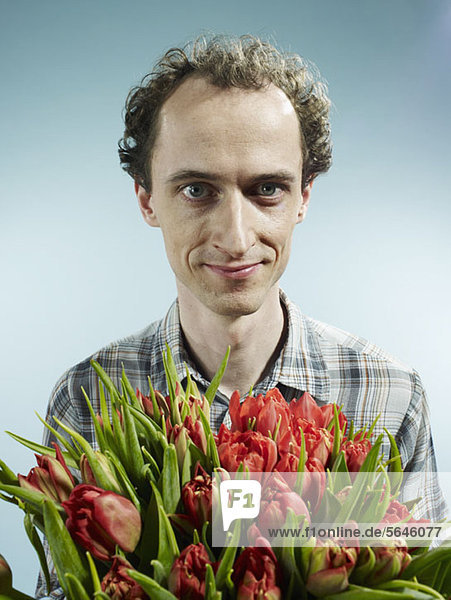 Ein Mann  der einen Strauß Tulpen hält.