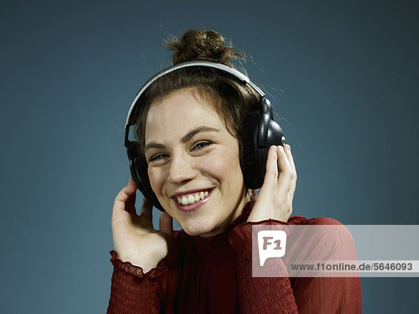 Eine junge hippe Frau mit Kopfhörern und einem Lächeln.