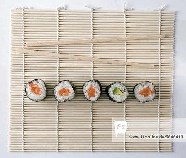 Sushi und Essstäbchen auf einer Holzmatte