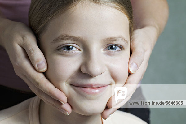 Portrait of daughter with Mother's hands on her cheeks