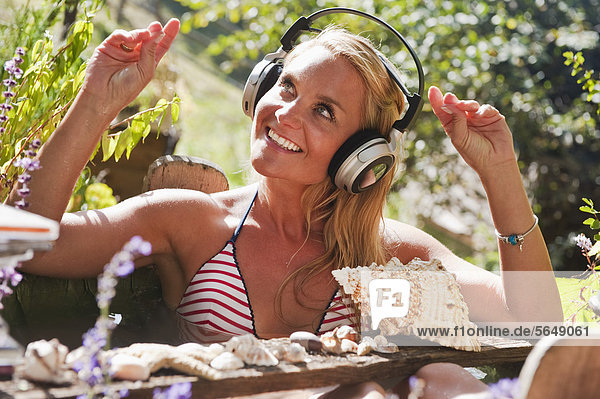 Austria Salzburg Flachau Young woman sitting in tun with water and listening music