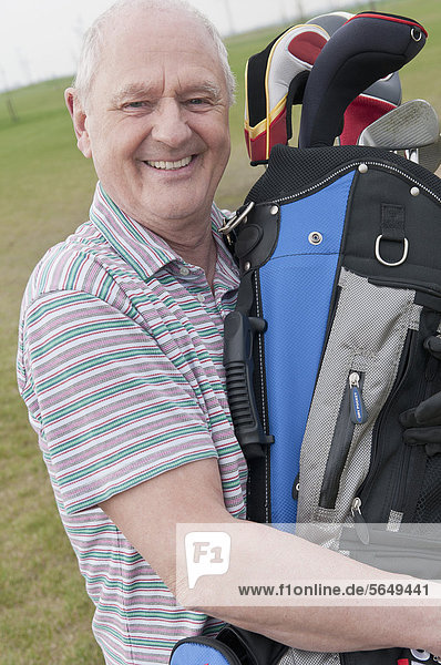 Germany  North Rhine Westphalia  Duesseldorf  Golfer with golf bag  portrait