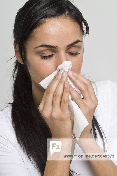 Young woman blowing her nose in handkerchief