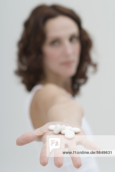 Mid adult woman showing white pills in hand