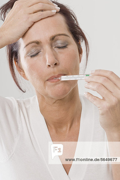 Reife Frau mit Thermometer im Mund Portrait