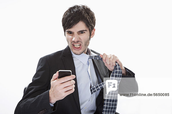 Businessman looking at mobile phone and removing tie